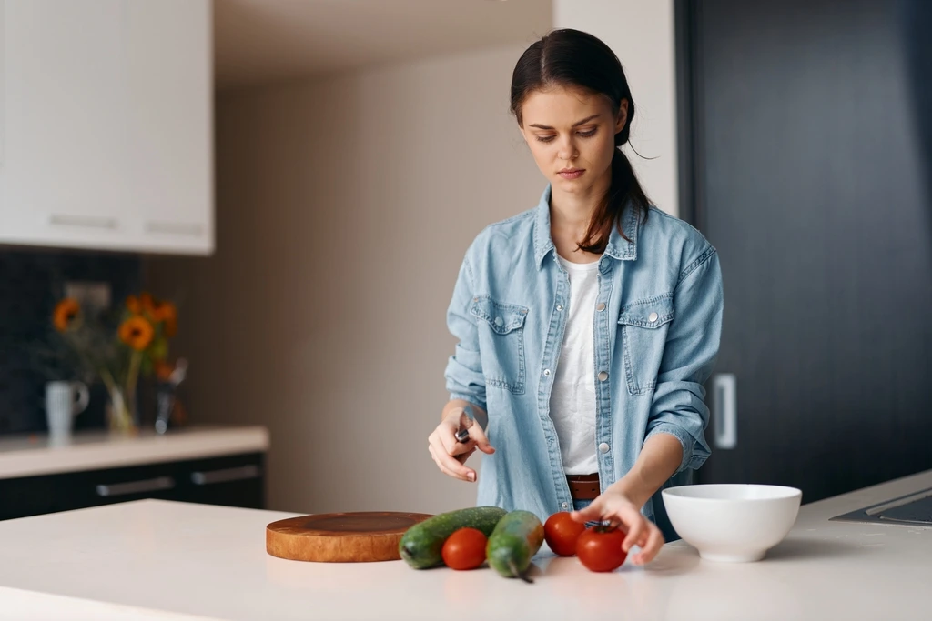 Mia Rodriguez carefully selecting a fresh tomato while preparing a healthy meal in her kitchen.