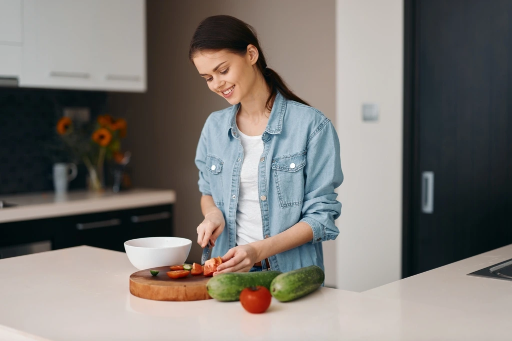 Mia Rodriguez smiling as she chops fresh tomatoes and cucumbers for a new recipe for her USA audience.