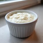 A close-up of creamy horseradish sauce with a zesty texture served in a small white fluted ramekin.