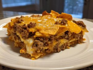 A generous slice of Dorito Casserole layered with seasoned ground beef, melted cheese, and crunchy tortilla chips.
