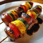 Two perfectly charred grilled vegetable skewers featuring zucchini, bell peppers, and onions, drizzled with a dark glaze.