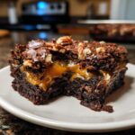 Close-up of a rich Turtle Brownies square showing a gooey caramel layer between dark chocolate cake and pecan topping.