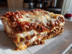 Close-up of a thick, layered slice of Lasagna with Cottage Cheese, topped with melted mozzarella and rich meat sauce.
