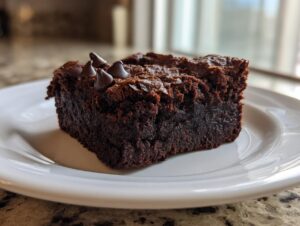A single, fudgy square of sweet potato brownies topped with chocolate chips, served on a white plate.