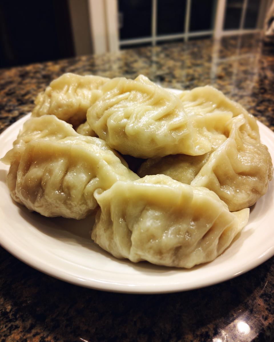 A close-up of several freshly steamed Traditional Chinese Dumplings piled on a white plate.