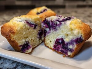 Close-up of a blueberry cream cheese muffin cut in half showing the moist interior and purple berry pockets.