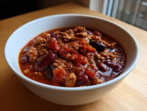 Close-up of a white bowl filled with rich, hearty high protein chili featuring ground meat and kidney beans.