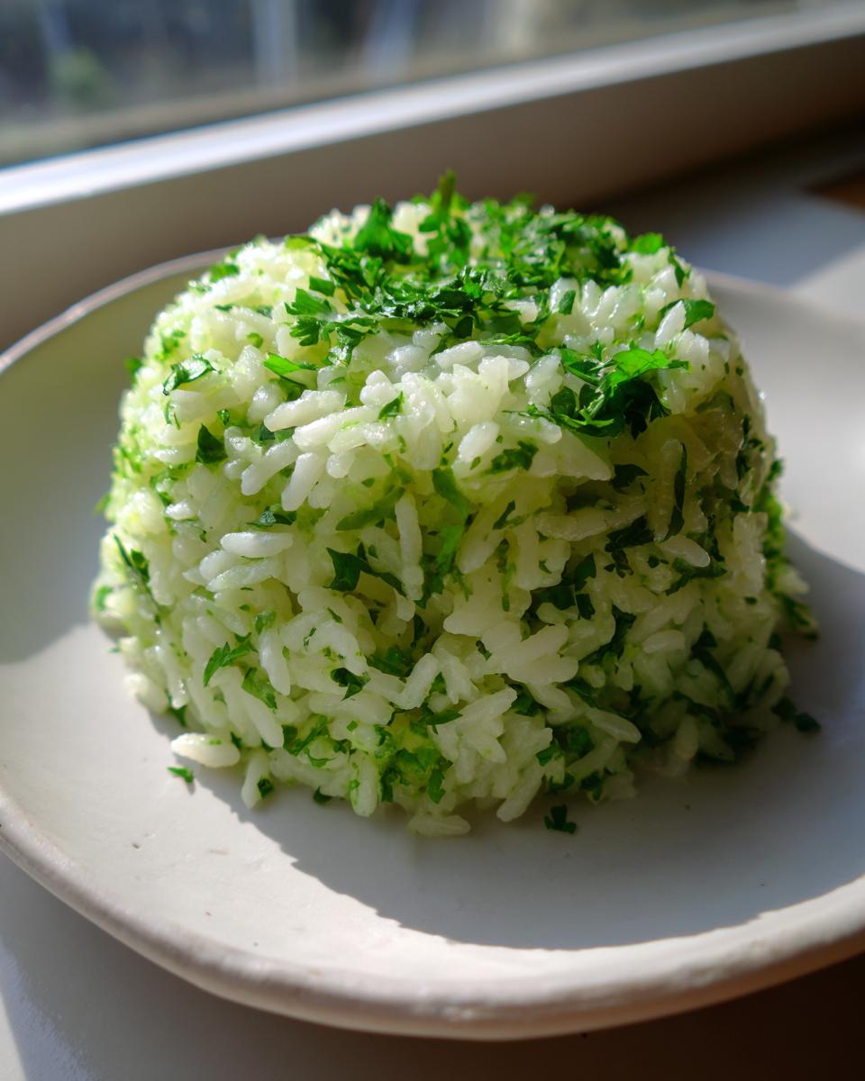 A perfectly molded serving of bright, fluffy cilantro lime rice topped with chopped green herbs.