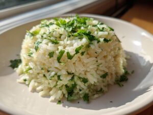 A perfectly molded serving of fluffy cilantro lime rice topped with fresh chopped herbs on a light plate.