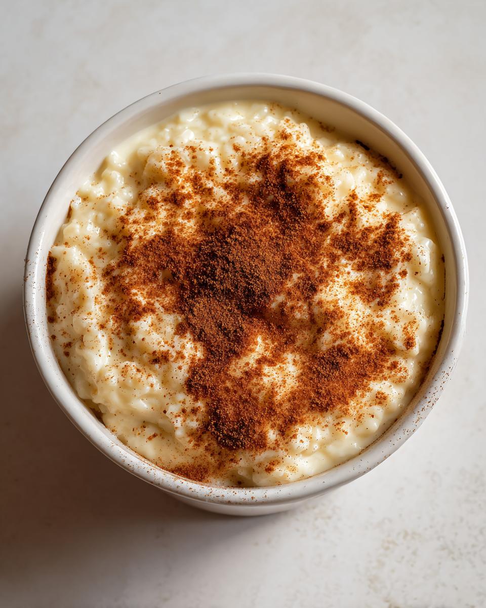 Overhead view of a bowl of creamy rice pudding generously dusted with ground cinnamon.