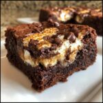 A close-up of a fudgy hot chocolate brownies slice topped with toasted marshmallow and chocolate chips.