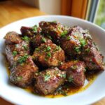 Close-up of tender, saucy crockpot steak cubes garnished generously with fresh chopped parsley.