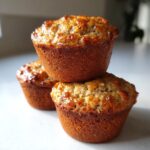 Close-up of three moist honey bran muffins stacked, showing a golden-brown, glazed top.