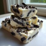 A stack of creamy white Oreo fudge squares loaded with dark chocolate cookie pieces.