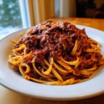 A hearty serving of pasta topped generously with rich, slow-cooked bolognese sauce.