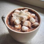 Close-up of a mug filled with rich hot chocolate topped generously with fluffy marshmallows.