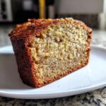 Close-up view of a thick slice of moist sugar free banana bread on a white plate.