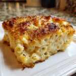 A thick, creamy slice of southern baked macaroni and cheese featuring elbow pasta and a golden, crispy, herbed topping.