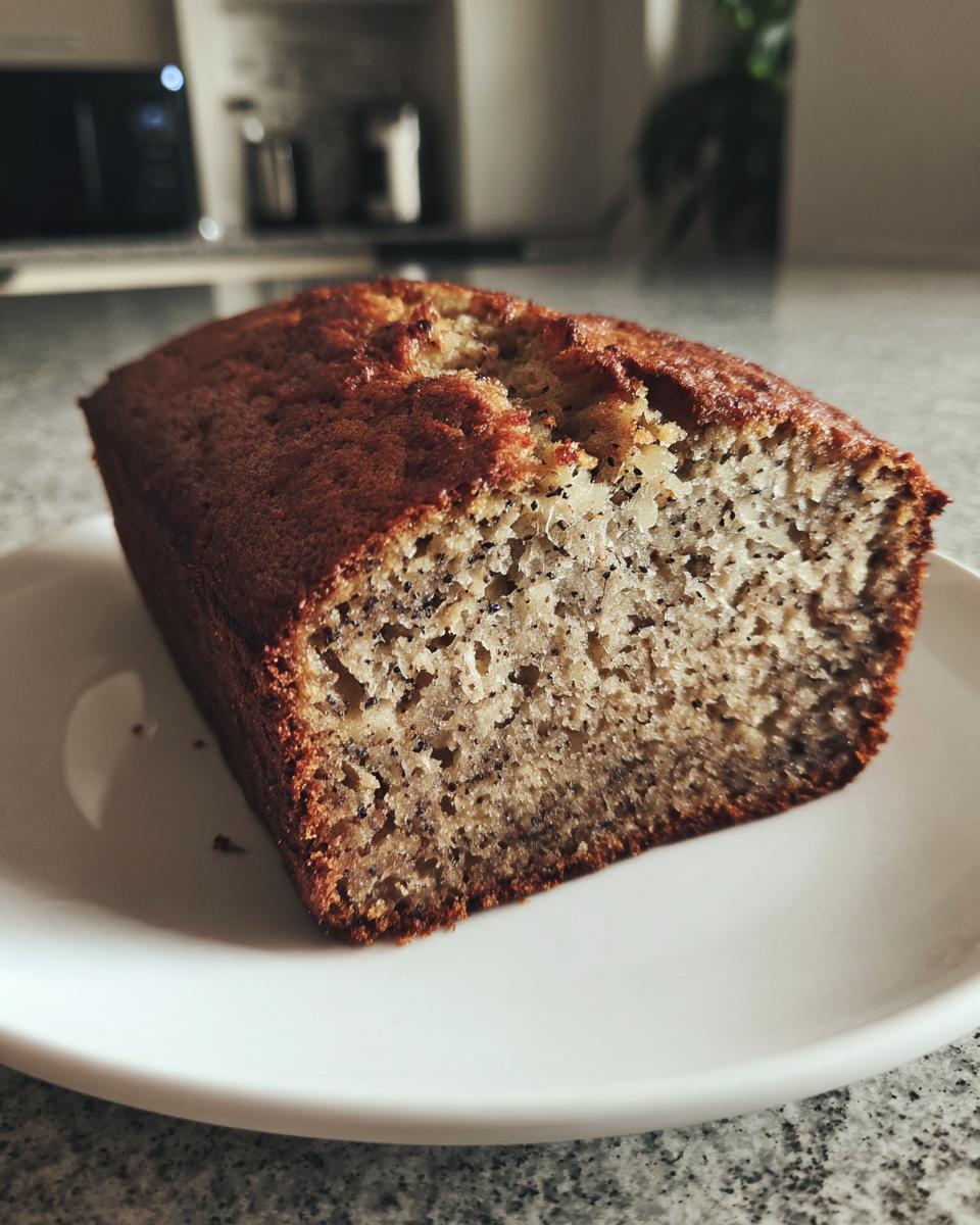 A loaf of moist sugar free banana bread with a dark golden crust, sliced to show the texture.