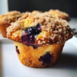 A close-up of a tender blueberry muffin topped with a generous layer of brown sugar streusel.