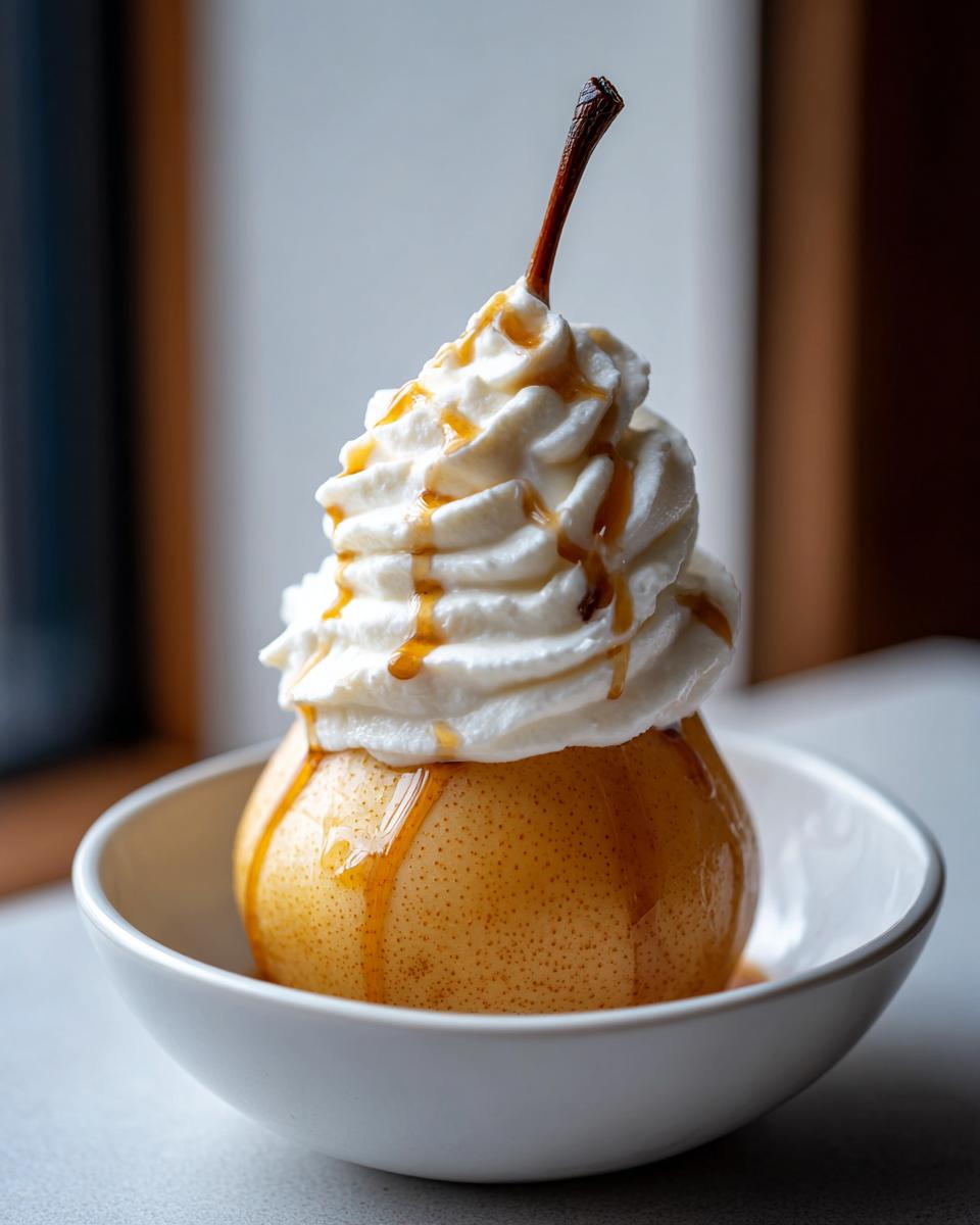 A perfectly cooked poached pear topped with a swirl of whipped cream and drizzled with caramel sauce.