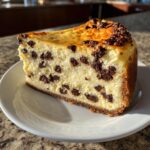A close-up of a perfect slice of creamy chocolate chip cheesecake on a white plate.