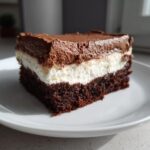 A square slice of rich, layered Italian Love Cake featuring a dark chocolate base, white cream layer, and chocolate mousse topping.