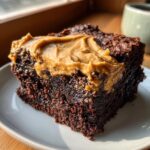 Close-up of a rich, dark chocolate banana bread brownies slice topped with creamy peanut butter frosting.
