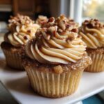 Close-up of a delicious pecan pie cupcake topped with swirled caramel frosting and chopped pecans.