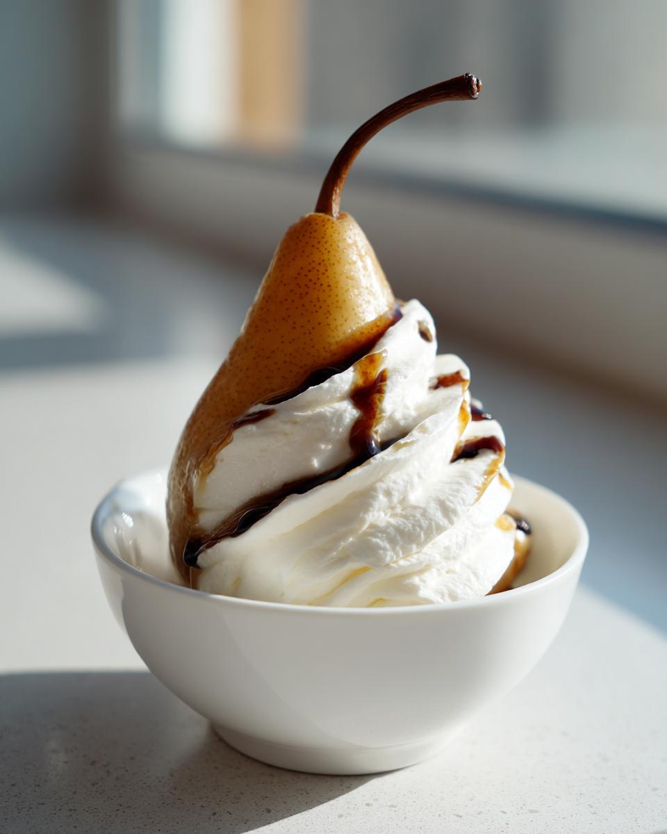 A single whole poached pear served upright in a white bowl, topped with a swirl of whipped cream and drizzled with dark syrup.