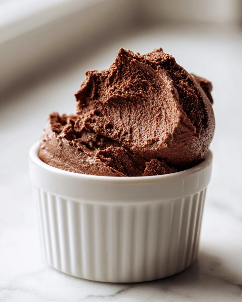 A close-up of rich, dark chocolate mousse scooped high in a white fluted ramekin.