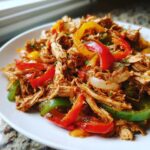 Close-up of shredded chicken mixed with colorful bell peppers and onions, ready for crockpot chicken fajitas.