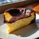 A creamy slice of Basque burnt cheesecake showing its signature dark, caramelized top and rich yellow interior.