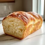 A freshly baked loaf of japanese milk bread, sliced to show its incredibly soft, feathery interior and golden-brown top.