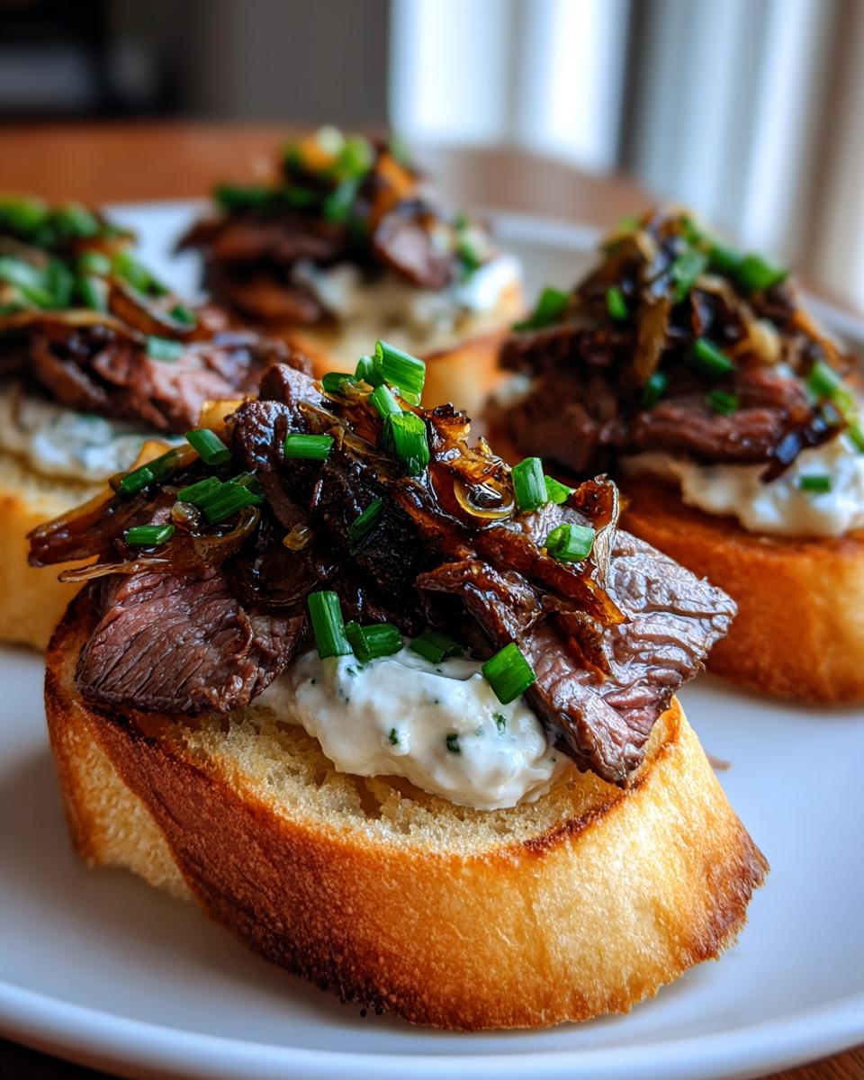 Close-up of gourmet steak crostini topped with creamy spread, sliced steak, caramelized onions, and chives.