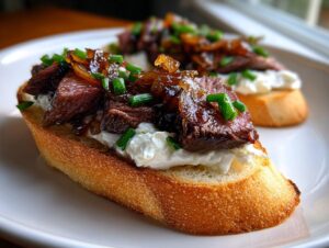 Close-up of a delicious steak crostini topped with creamy cheese, caramelized onions, and fresh chives.